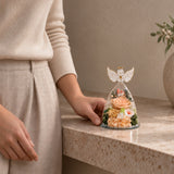 Compact Champagne Angel Wings Keepsake beside a seated person for scale