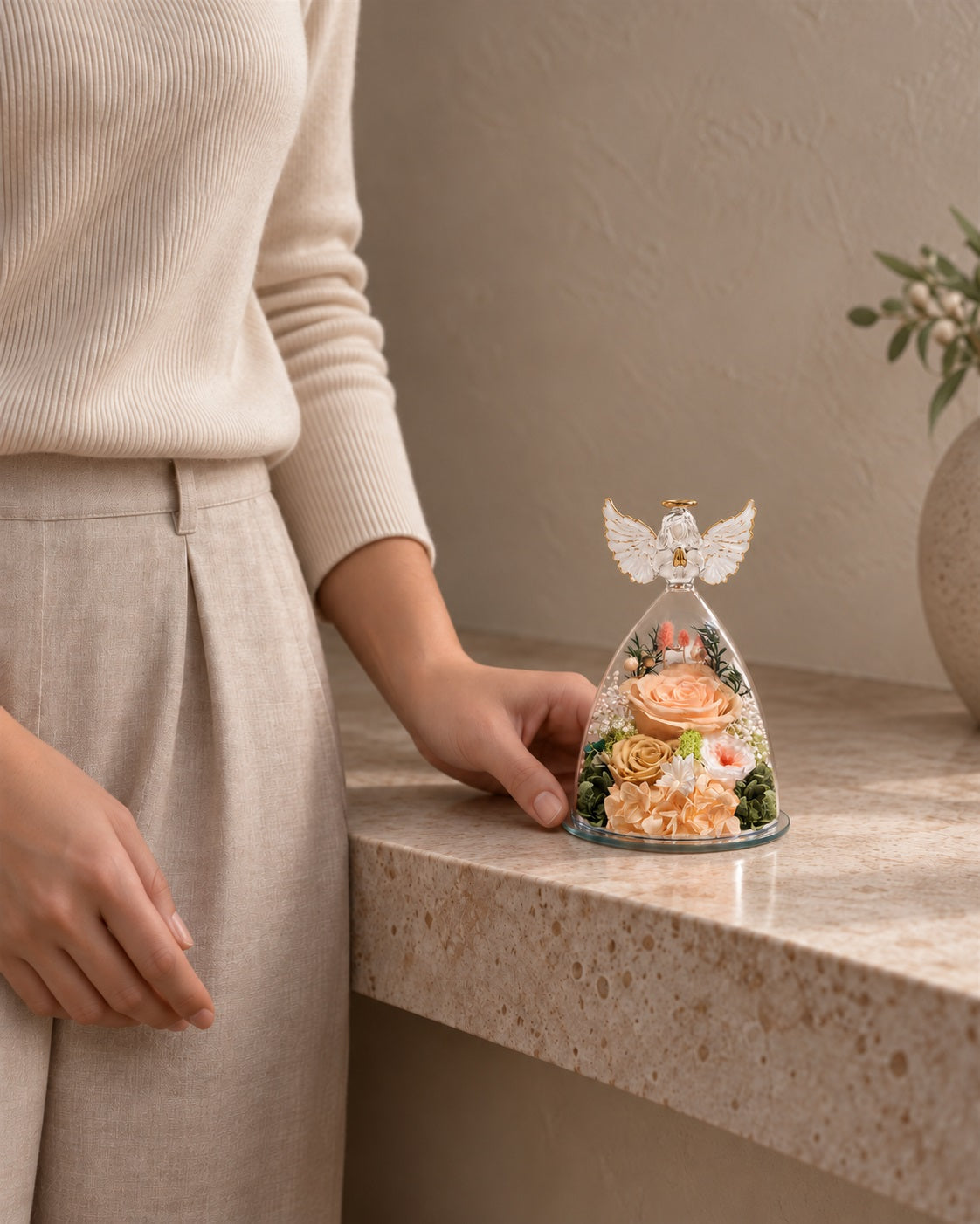 Compact Champagne Angel Wings Keepsake beside a seated person for scale